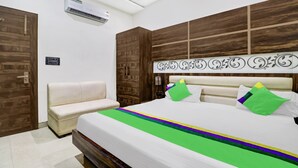 A bedroom with a bed, a bench, wooden wardrobe, and an air conditioning unit. - Itsy Hotels Anjali Mahal 500, Mtrs From Mathura Railway Station (Mathura)