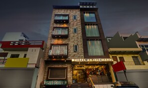 Een meerlaags hotel met balkons, een bord met de tekst 'HOTEL ANJALI MAHAL' en een zichtbare ingang.