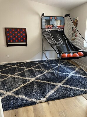 A basketball hoop, a patterned rug, and a wall-mounted game board.