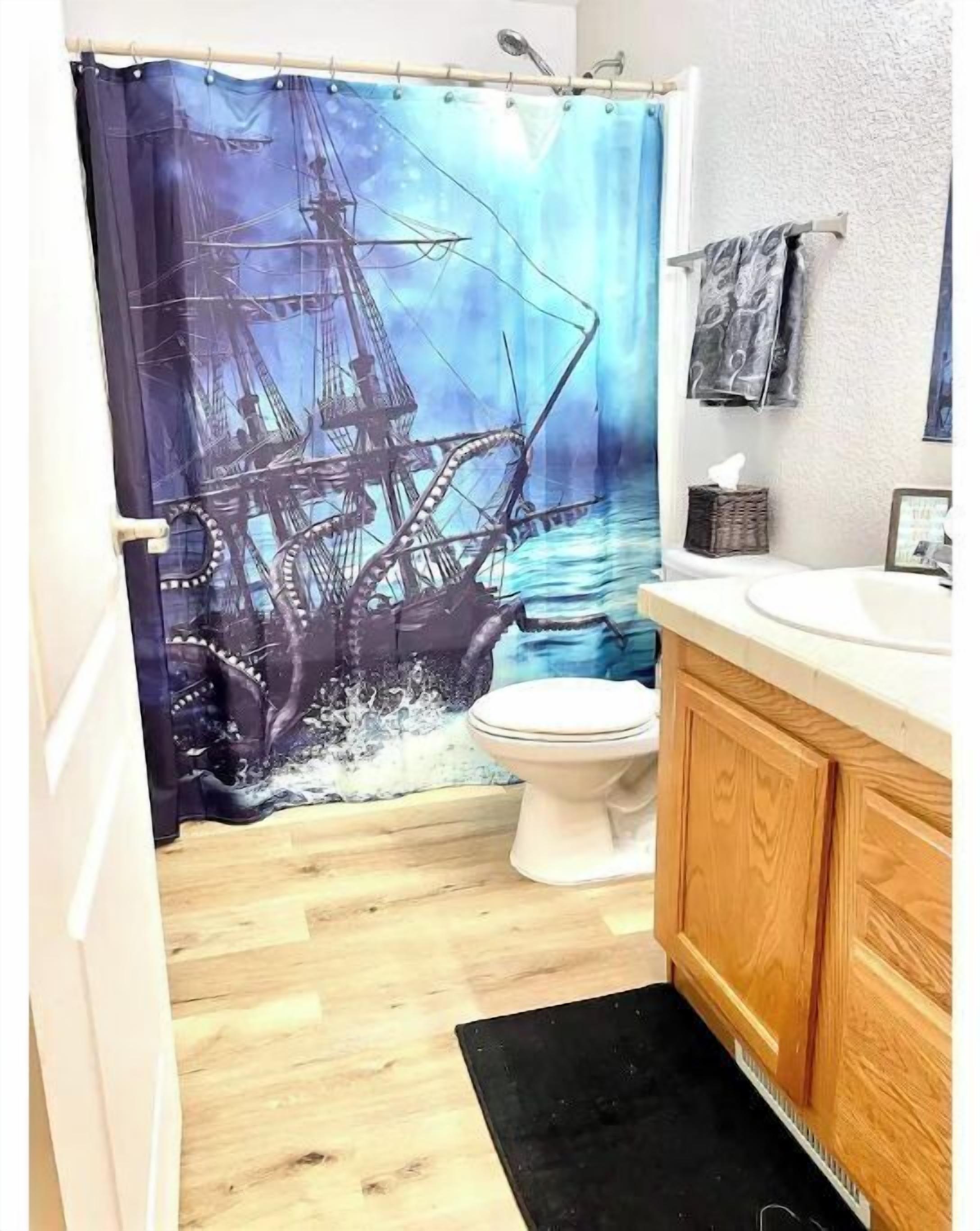 Un bagno con tenda da doccia a tema nave, un water, mobili in legno e un piccolo tappeto.