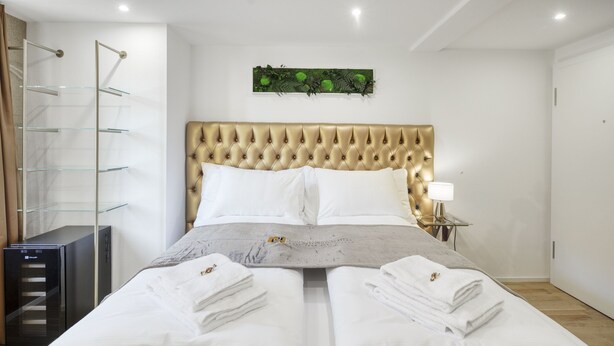 Una cama bien hecha con sábanas blancas y dos toallas sobre ella.
