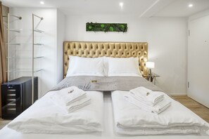 Un lit bien fait, avec du linge de lit blanc et deux serviettes posées sur le lit.