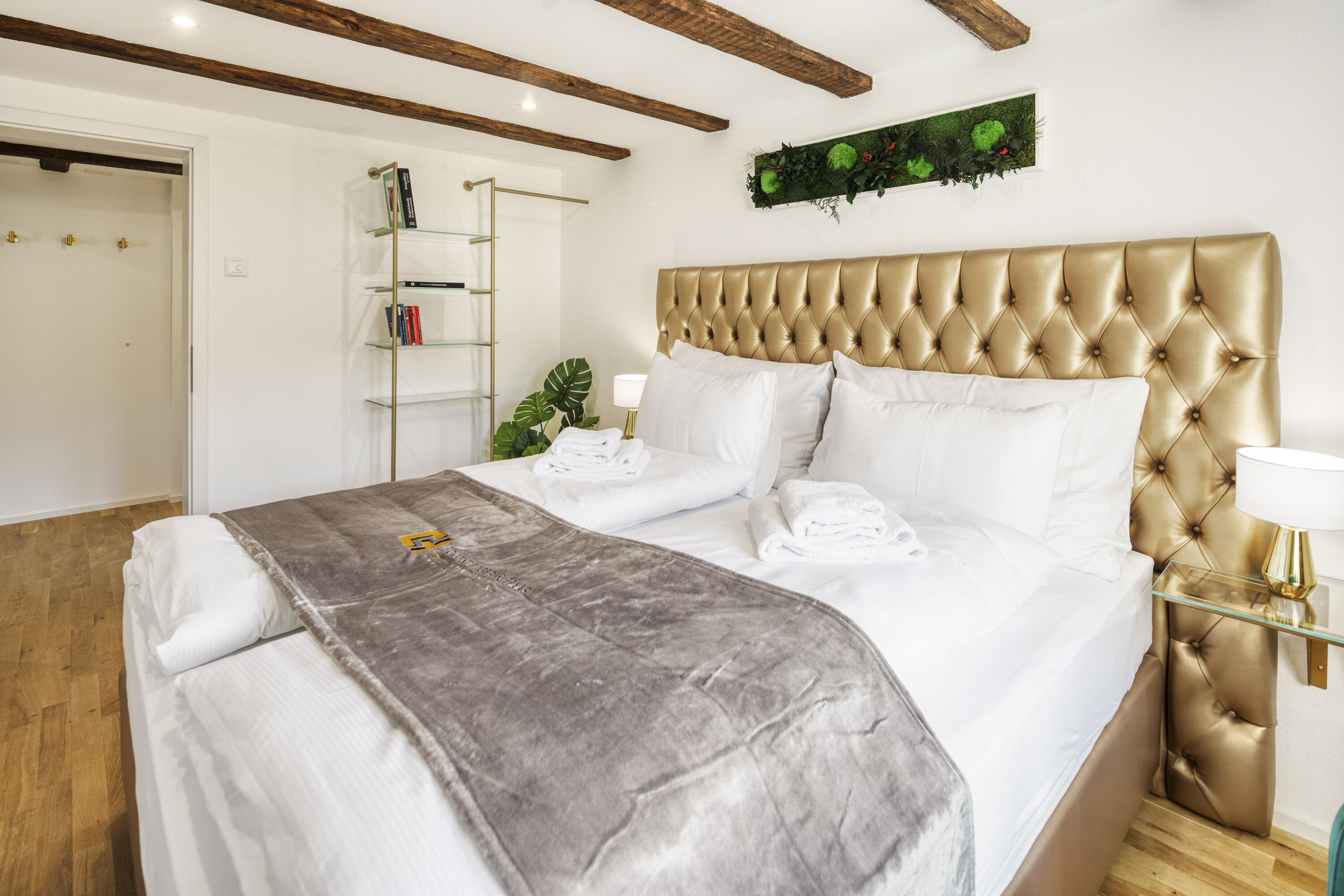 Ein Schlafzimmer mit einem großen Bett, einem Nachttisch, einem an der Wand befestigten Regal und einer Tür.