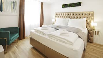 Ein modernes Hotelzimmer mit einem großen Bett, einem grünen Sessel und Blick auf die Stadt.