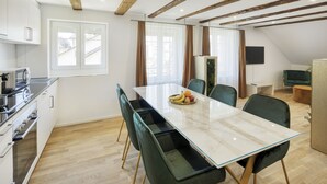 Una cocina moderna con zona de comedor, vigas de madera y un ventanal grande.