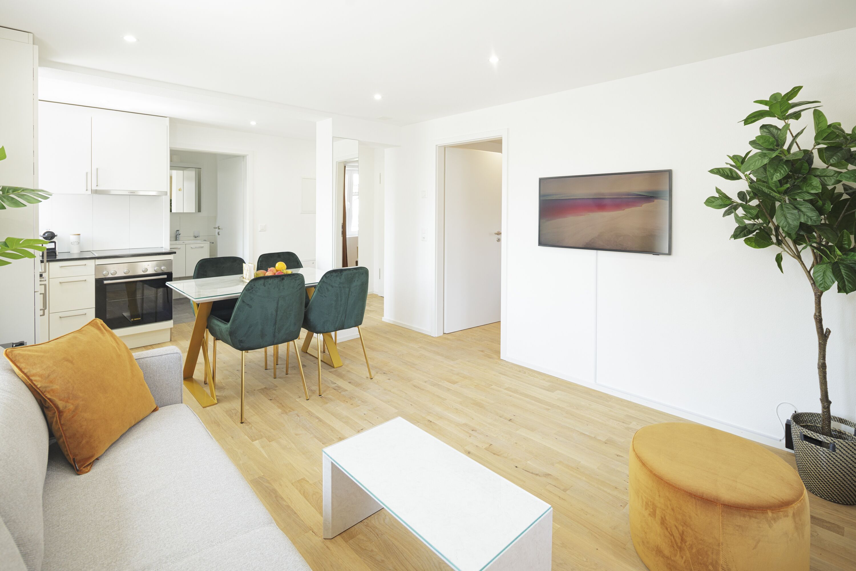 A modern living room with a sofa, a coffee table, and a dining area with chairs and a table.