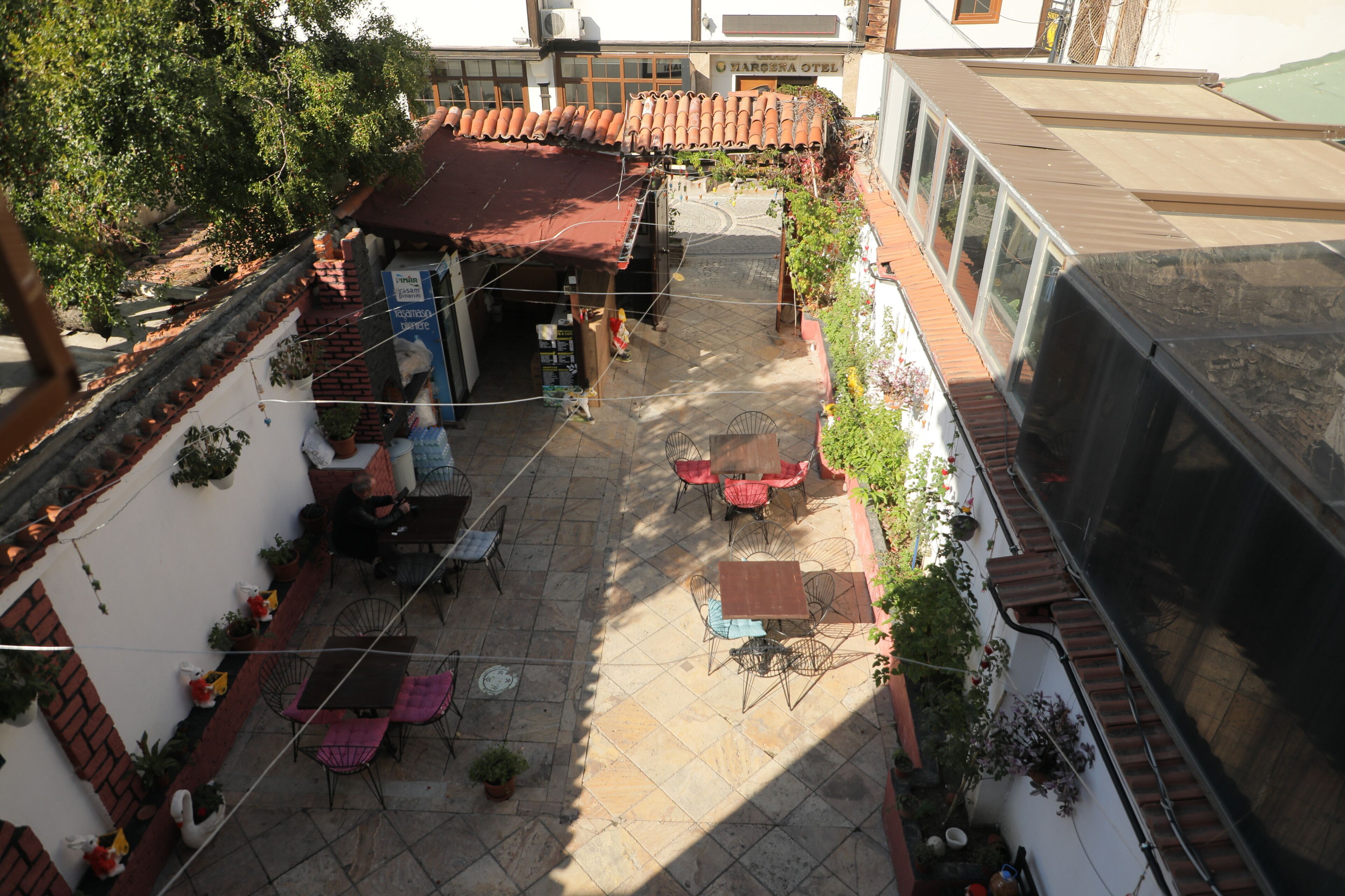 Un patio con mesas al aire libre, una pequeña tienda y un edificio de techo con tejas.