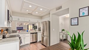 Una cocina moderna con armarios blancos, electrodomésticos de acero inoxidable y una mesa de comedor de madera.
