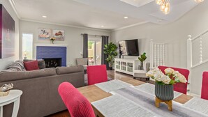 Una sala de estar moderna con sofá, mesa de comedor, sillas, chimenea y televisor.