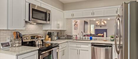 A modern kitchen with white cabinetry, stainless steel appliances, and a central island.