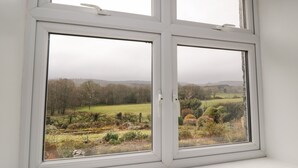 Une fenêtre donnant sur un paysage rural, avec des champs et des arbres.