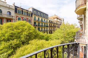 A row of multi-story buildings with balconies, surrounded by lush green trees.
