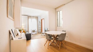 Una sala de estar moderna con una mesa de comedor redonda, sillas grises, un sofá gris y una pequeña mesa auxiliar.