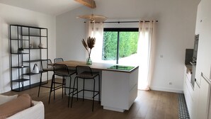 Una cucina moderna con isola centrale, sedie nere, un divano bianco e un soffitto in legno.
