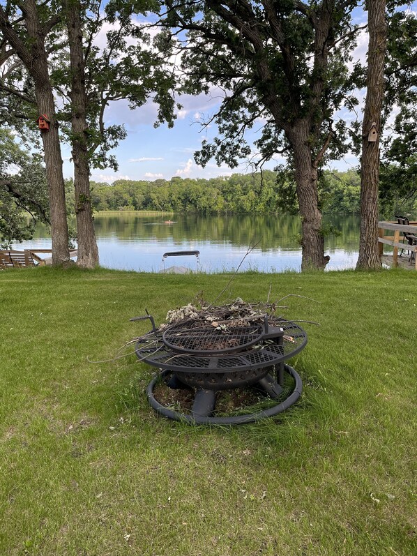 Een oevergebied met een vuurkuil en picknicktafel.