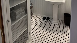 Un baño con un lavamanos blanco, un espejo grande y un armario con cestas de ropa.