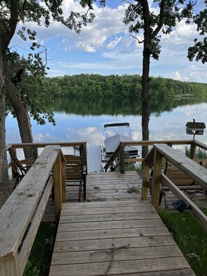 A wooden dock leading to a lake with a boat docked at the end.