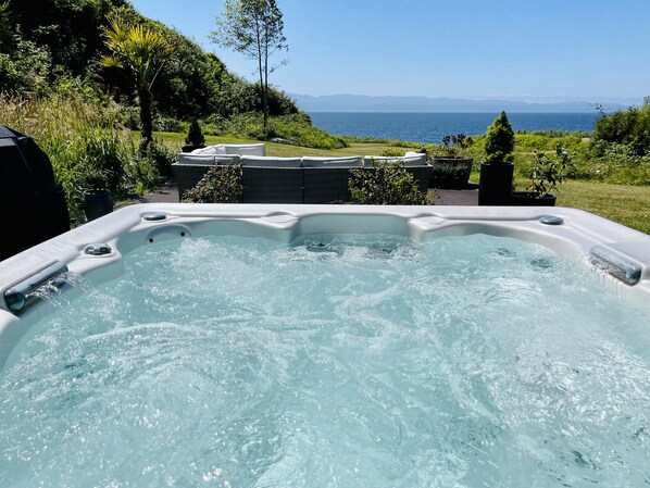 A hot tub with a view of the sea and mountains.