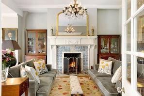 A traditional living room with a fireplace, two sofas, a chandelier, and a cabinet. - Colleton Hall - Six Bedroom Villa, Sleeps 12 (Rackenford)