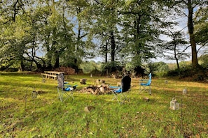 An outdoor camping area with trees, a wooden bench, and camping chairs. - Colleton Hall - Six Bedroom Villa, Sleeps 12 (Rackenford)