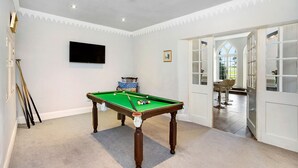 A room with a pool table, a television mounted on the wall, and a door leading to a dining area. - Colleton Hall - Six Bedroom Villa, Sleeps 12 (Rackenford)