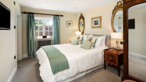 A hotel room with a bed, bedside tables, a mirror, and a window with curtains. - Colleton Hall - Six Bedroom Villa, Sleeps 12 (Rackenford)