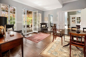 A spacious room with a dining table, chairs, a fireplace, and a view of the outdoors through large windows.