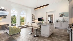 A modern kitchen with white cabinetry, a central island, and a dining area with bar stools.