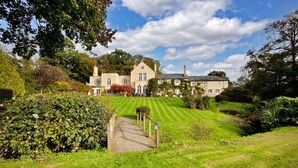 A large, two-story house with a well-maintained lawn and a paved pathway leading to the entrance.