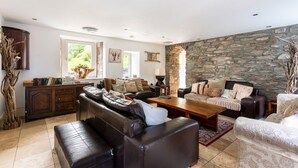 Un amplio salón con pared de piedra, sofás de cuero, una mesa de centro de madera y vistas al exterior.