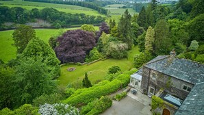 A large house with a stone roof and a garden with a variety of trees and a lawn. - Derwent Garden Estate (Bridekirk)