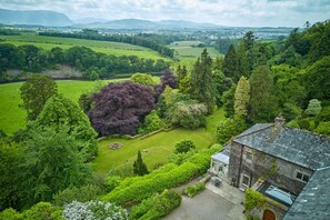 A large house with a stone roof and a garden with a variety of trees and a lawn. - Derwent Garden Estate (Bridekirk)