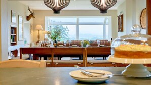 A dining area with a table set for four, a chandelier, and a deer head mounted on the wall. - Derwent Garden Estate (Bridekirk)