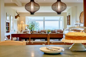 Un comedor con una mesa dispuesta para cuatro personas, un candelabro y una cabeza de venado montada en la pared.
