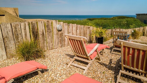 A patio with wooden chairs and a red cushion, overlooking a beach. - Meadow Manor - Seven Bedroom Villa, Sleeps 14 (Mundesley)