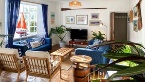 A living room with a sofa, chairs, a television, and a large window with curtains. - Meadow Manor - Seven Bedroom Villa, Sleeps 14 (Mundesley)