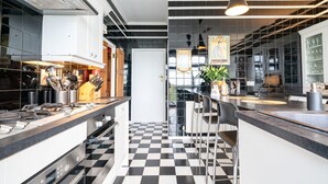 A modern kitchen with a black and white checkered floor, stainless steel appliances, and bar stools. - Culver Down Manor - Seven Bedroom Villa, Sleeps 16 (Shanklin)
