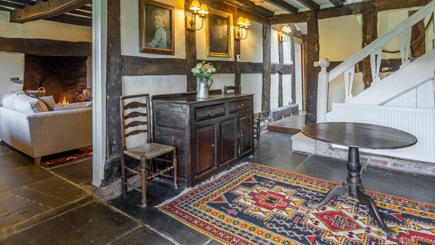 A cozy room with a fireplace, a dining table, and a sofa. - Tanat Valley Farmhouse (Hirnant)