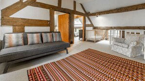 A modern living room with exposed wooden beams, a grey sofa, patterned cushions, and a patterned rug. - Tanat Valley Farmhouse (Hirnant)