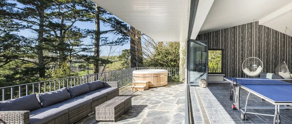 An outdoor deck with a seating area, a hot tub, and a ping pong table.