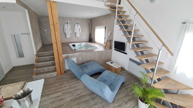 Un espace de vie moderne comprenant un escalier, un coin salon et un aménagement de type spa avec une baignoire.