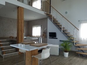 Um espaço de estar moderno com cozinha, sala de jantar e escada.