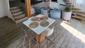 Un appartement moderne comprenant un coin repas, une cuisine, un salon et un escalier menant à une mezzanine.