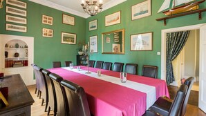 Une salle de conférence avec une longue table, des chaises et des tableaux encadrés accrochés aux murs.