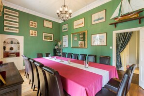 Une salle de conférence avec une longue table, des chaises et des tableaux encadrés accrochés aux murs.
