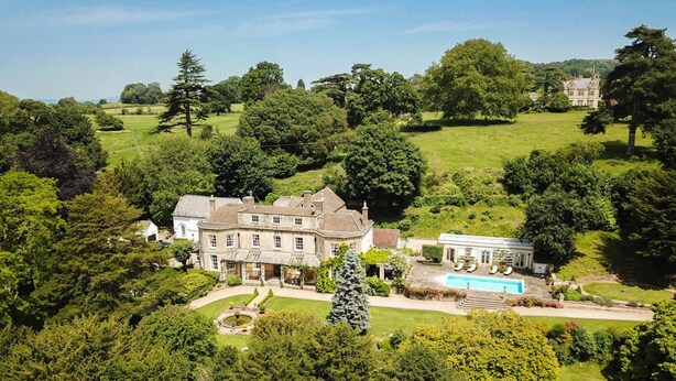 Un vaste domaine comprenant une maison principale, une piscine et de vastes jardins.