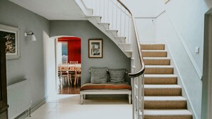 Una escalera con barandilla blanca que lleva a un rellano con un banco y cojines.