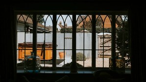 Una ventana con vistas a un jardín, una estructura de madera y una valla metálica.