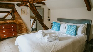 Un dormitorio con una cama grande, cómoda de madera y paredes de ladrillo visto.