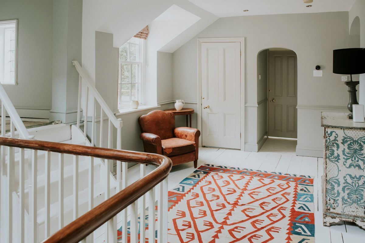 A spacious room with a white staircase, a patterned rug, and a door leading to another room.
